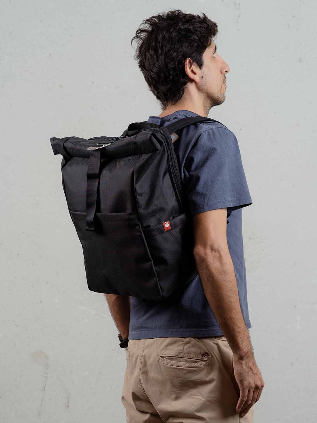 Hombre de espaldas usando morral enrollable de viaje Mont 24L